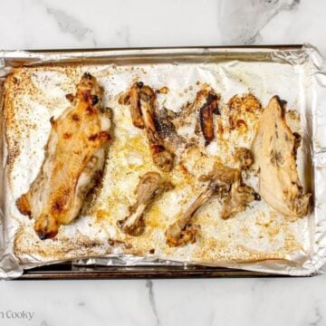 Roasted chicken carcass on a sheet pan lined with foil.
