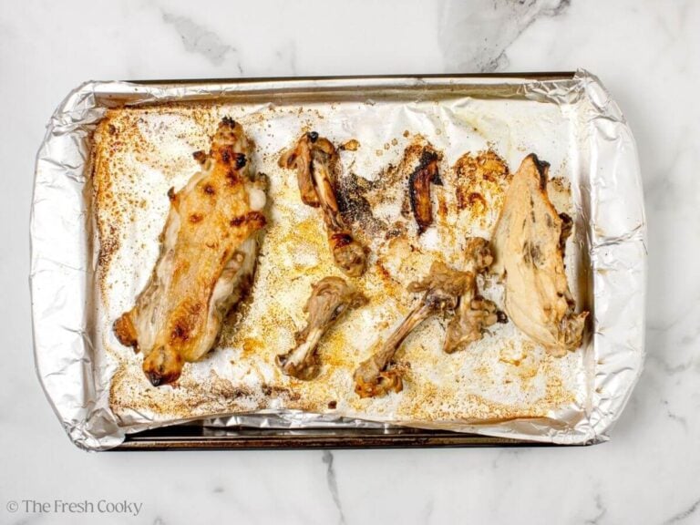 Roasted chicken carcass on a sheet pan lined with foil.