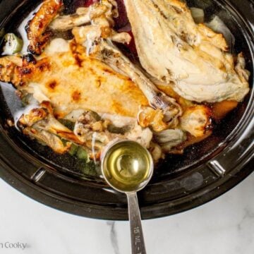 Apple cider vinegar being added to the broth ingredients in a slow cooker.