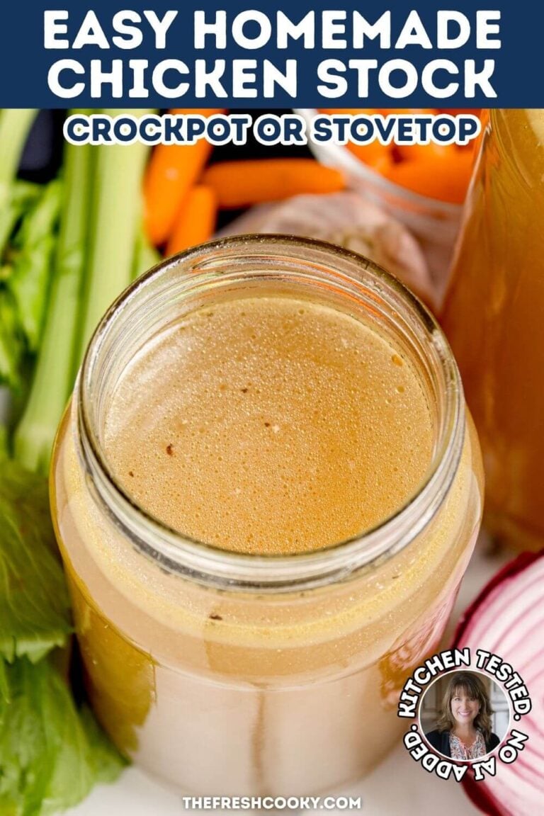 A glass jar of rich, golden chicken stock surrounded by carrots, garlic, red onion and celery, to pin.