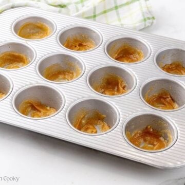 Honey glaze spread in the bottom of the muffin tin.