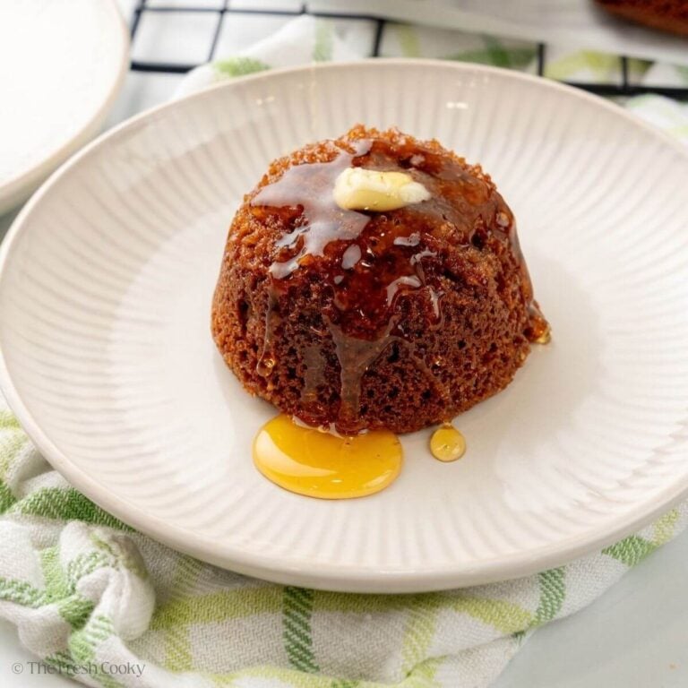 Finished honey bran muffin served on a plate with butter and more honey.