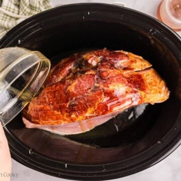 Spiral sliced ham in slow cooker, pouring honey butter mixture over the top and between slices.