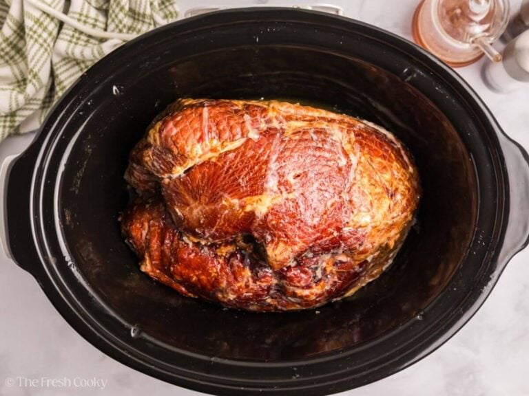 Ham flipped onto flat side inside a crockpot.