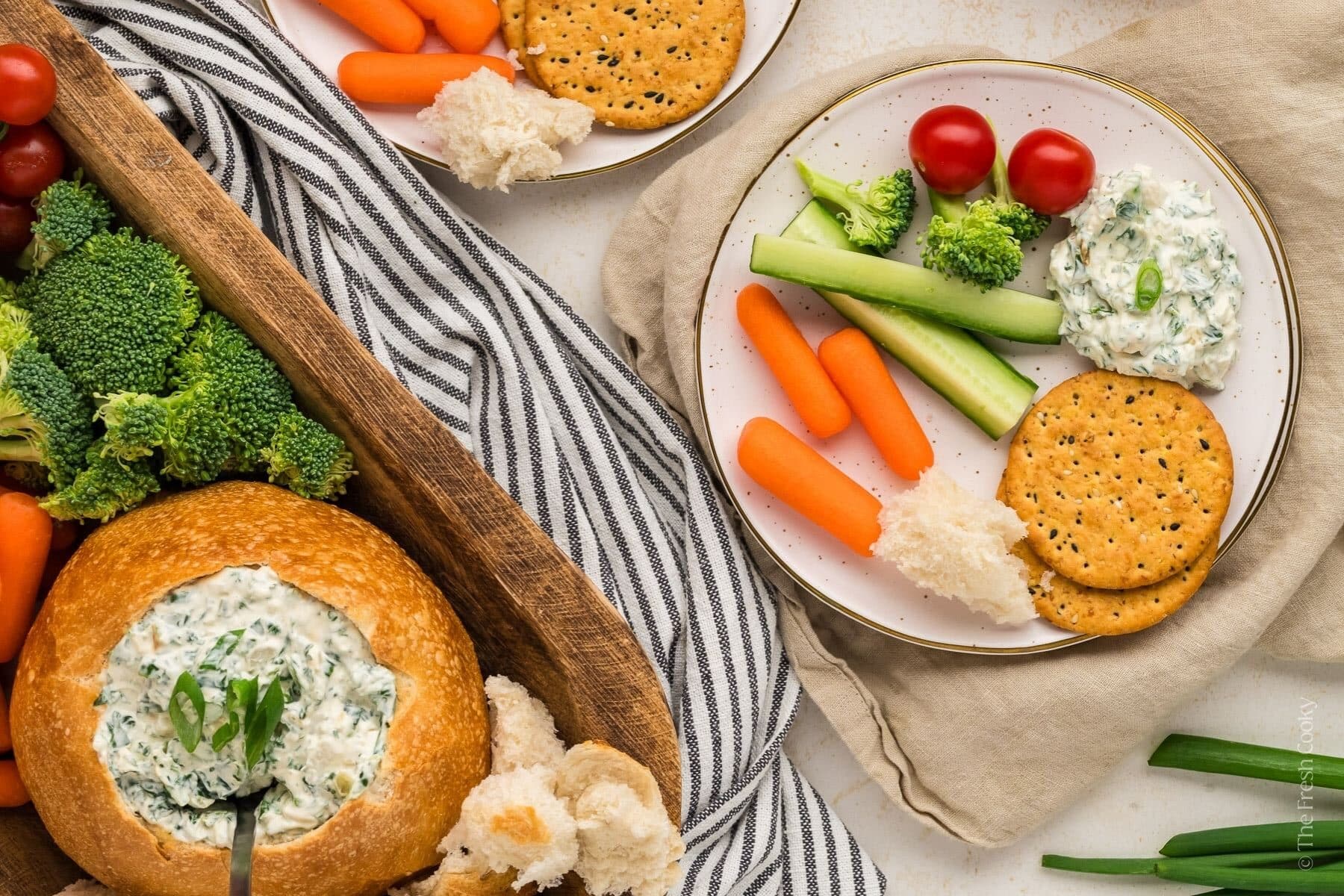 Spinach dip served ona plate with crackers and veggies.