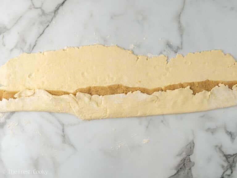 Almond paste being wrapped in the almond kringle pastry dough.