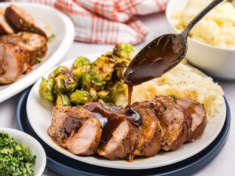 Drizzling maple glaze over the top of sliced maple dijon pork tenderloin on a plate.