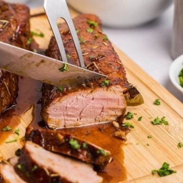 Using a fork and knife to cut into a maple dijon pork tenderloin.