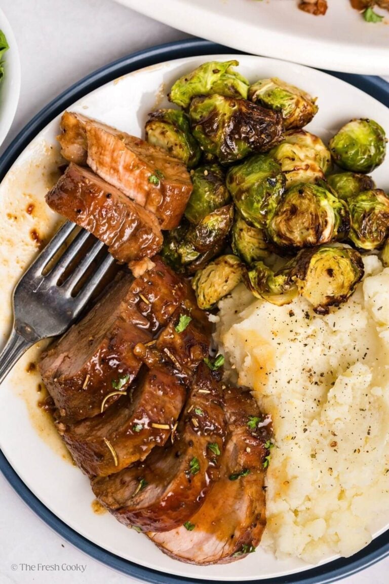 Overhead shot of a plate served with slices of maple dijon pork tenderloin served with mashed potatoes and Brussels sprouts.