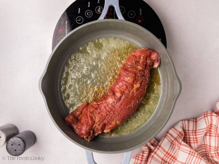 Pork tenderloin added to a skillet with butter in it.