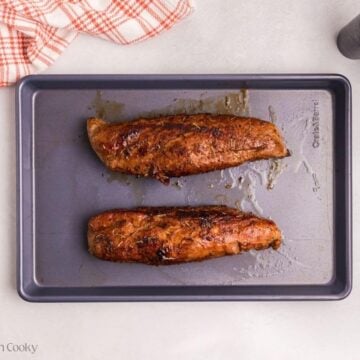 Two seared pork tenderloins on a sheet pan.