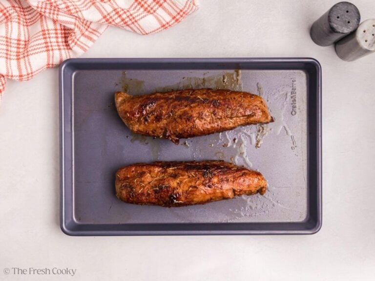 Two seared pork tenderloins on a sheet pan.
