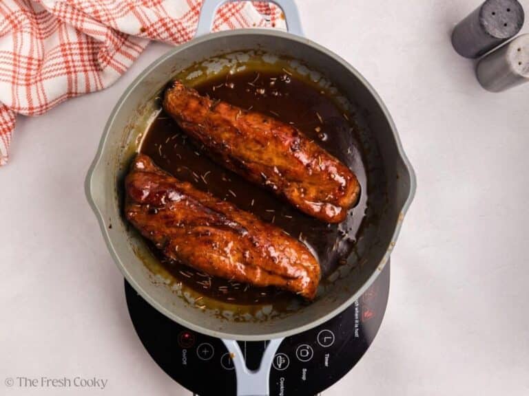 Pork tenderloins added back to the maple glaze in a skillet.
