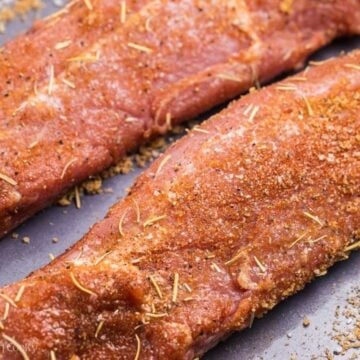 Close up of two pork tenderloins with spice rub on them.