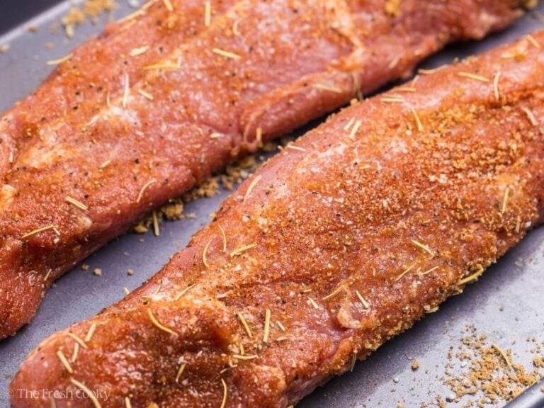 Close up of two pork tenderloins with spice rub on them.