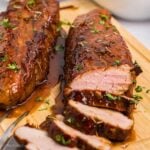 Sliced pork tenderloin on a wooden cutting board.