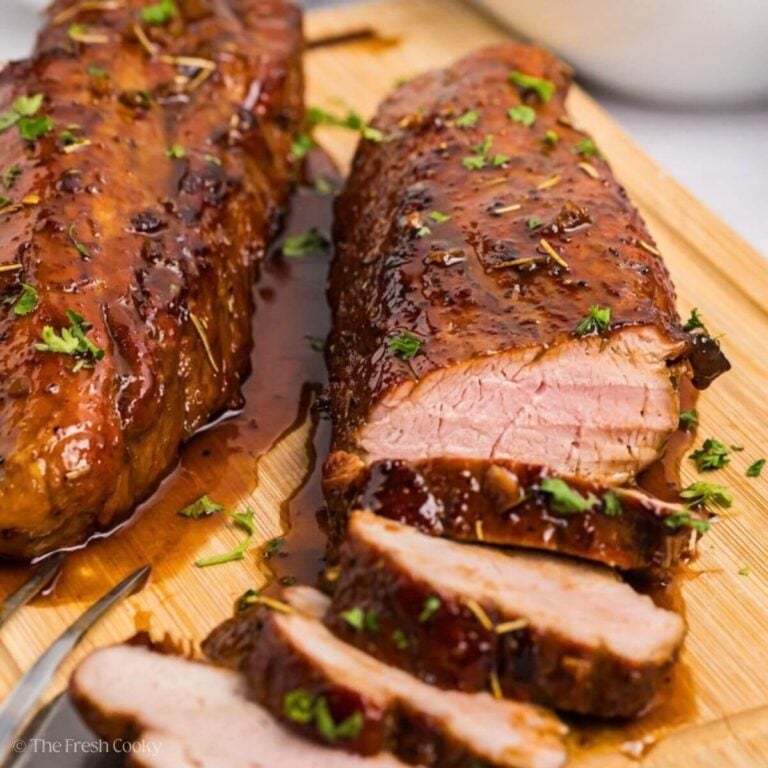 Sliced pork tenderloin on a wooden cutting board.