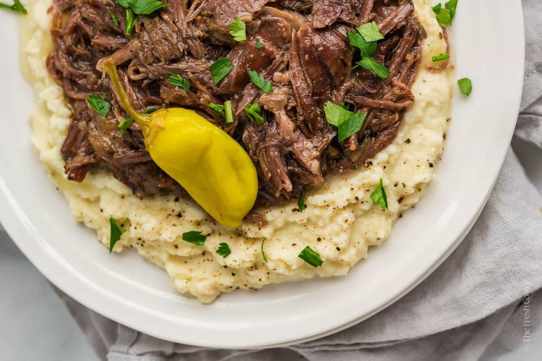 Overhead shot of shredded Mississippi pot roast beef on a bed of mashed potatoes.