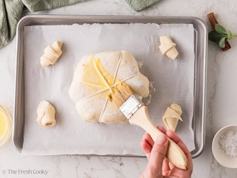 Brushing egg wash over twine-tied pumpkin baked brie.
