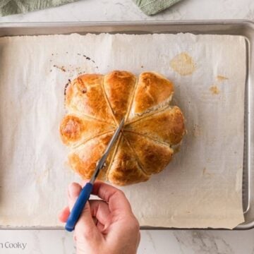 Hand with scissors snipping the string on the puff pastry.