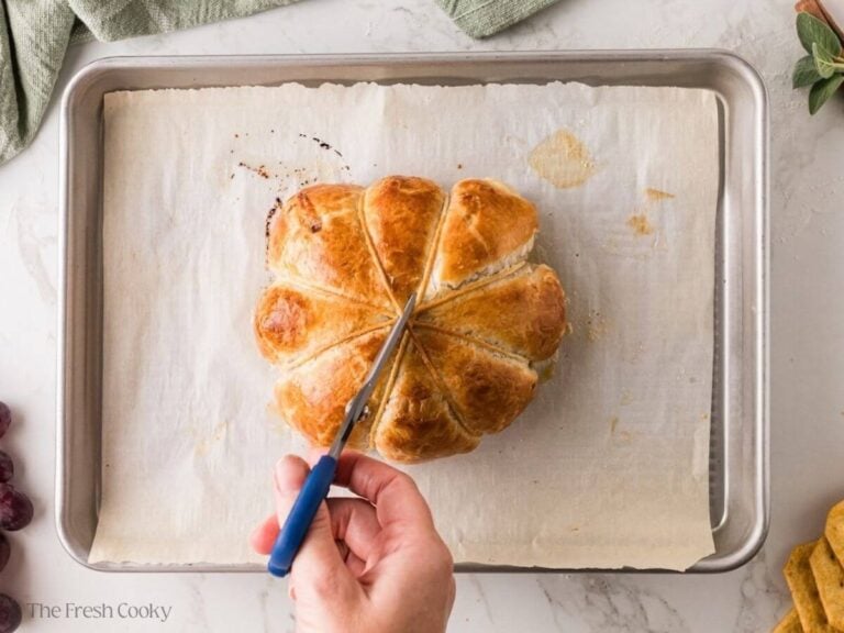 Snipping kitchen twine off a baked pumpkin brie.