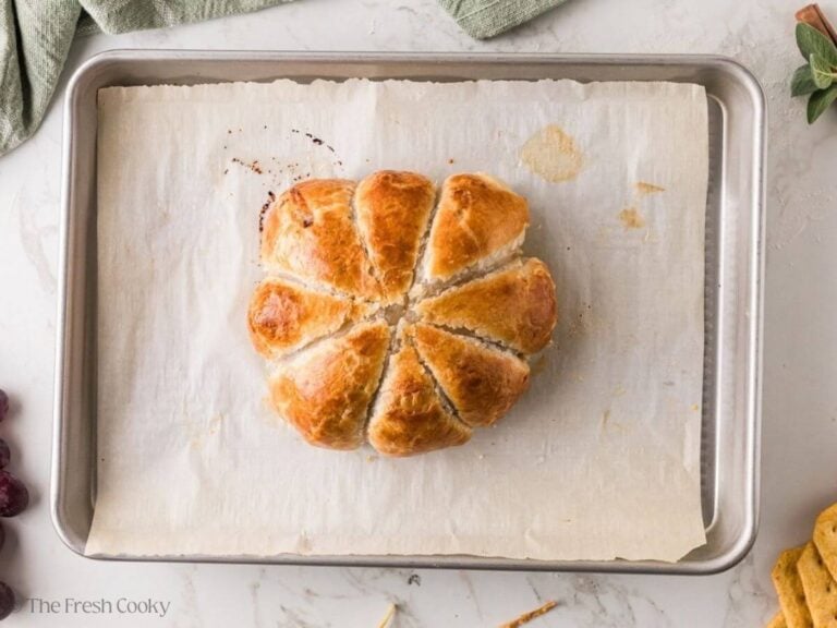 Twine snipped off the puff pastry baked brie on a baking sheet.