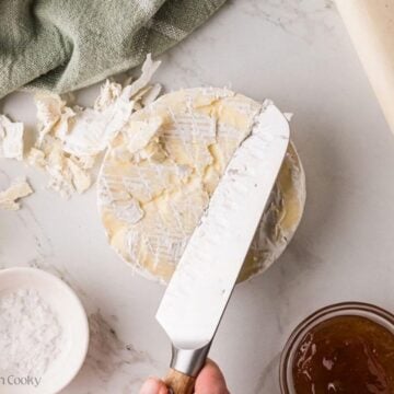 Trimming the rind off the top of a round of brie.