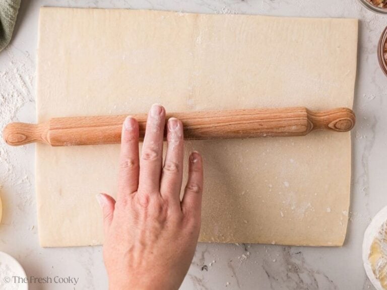 Thawed puff pastry rolled out on a floured surface.