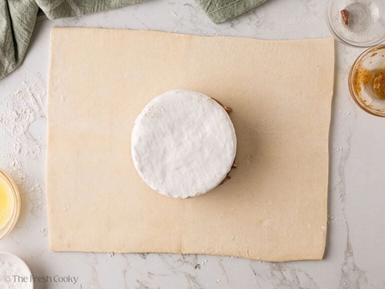 Wheel of brie set on fig jam and pecans, trimmed side down.