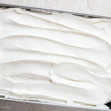 Whipped cream spread on top of the pumpkin poke cake.