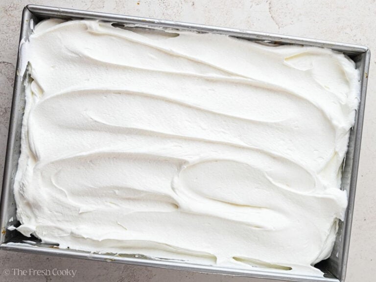 Whipped cream spread on top of the pumpkin poke cake.