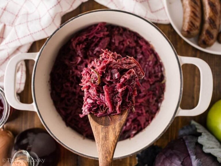 Wooden spoon with rotkohl on it hovering over the pot of cabbage.