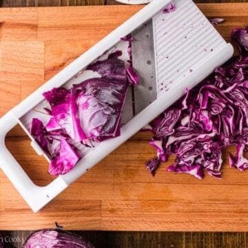 Shredding red cabbage on a mandolin.