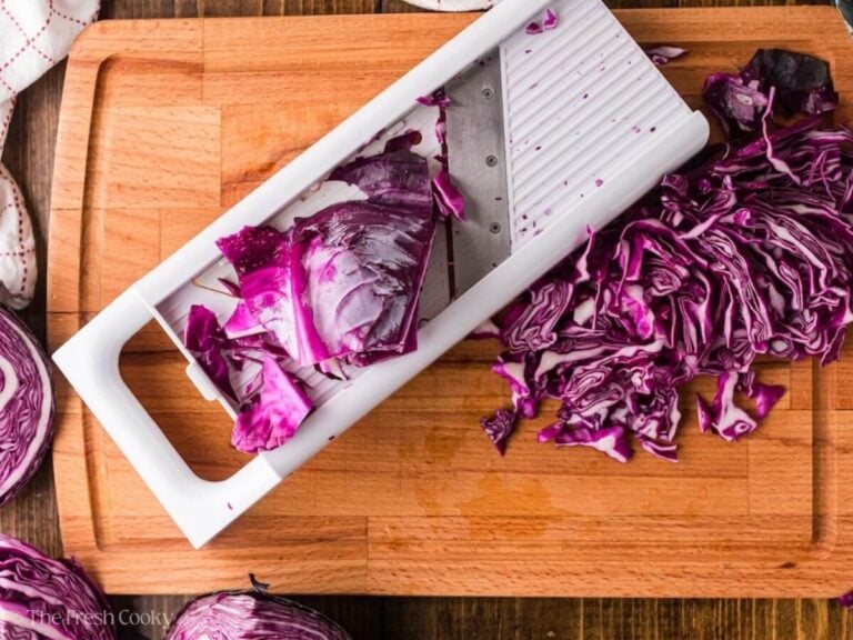 Shredding red cabbage on a mandolin.
