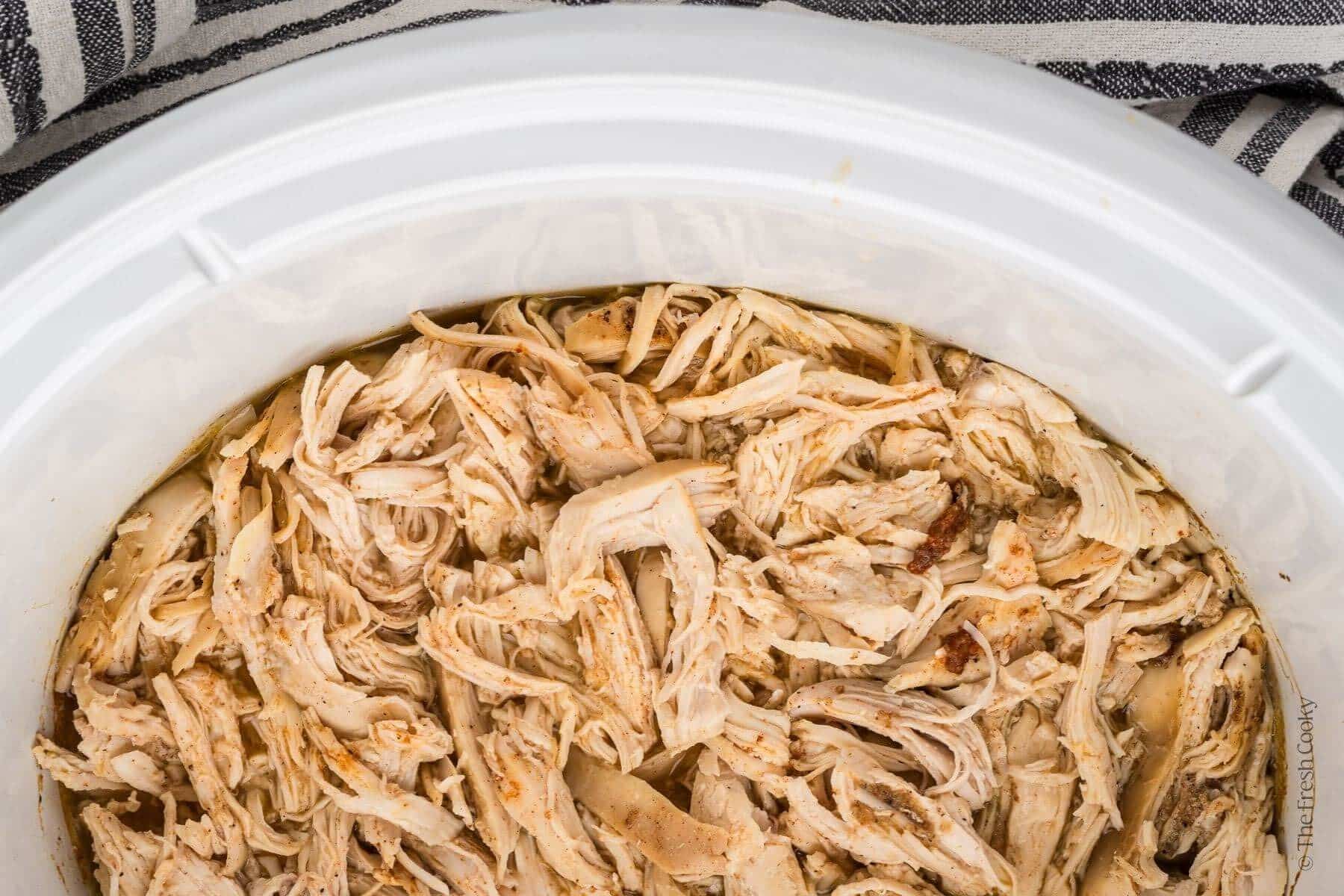 Overhead shot of shredded chicken in a slow cooker.