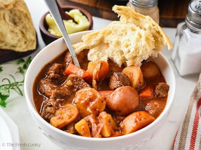 Bowl of slow cooker beef stew with a chunk of bread on the side.