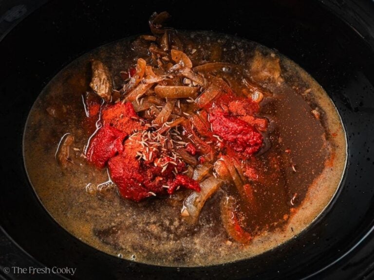 Broth, tomato paste, and spices added to the slow cooker.