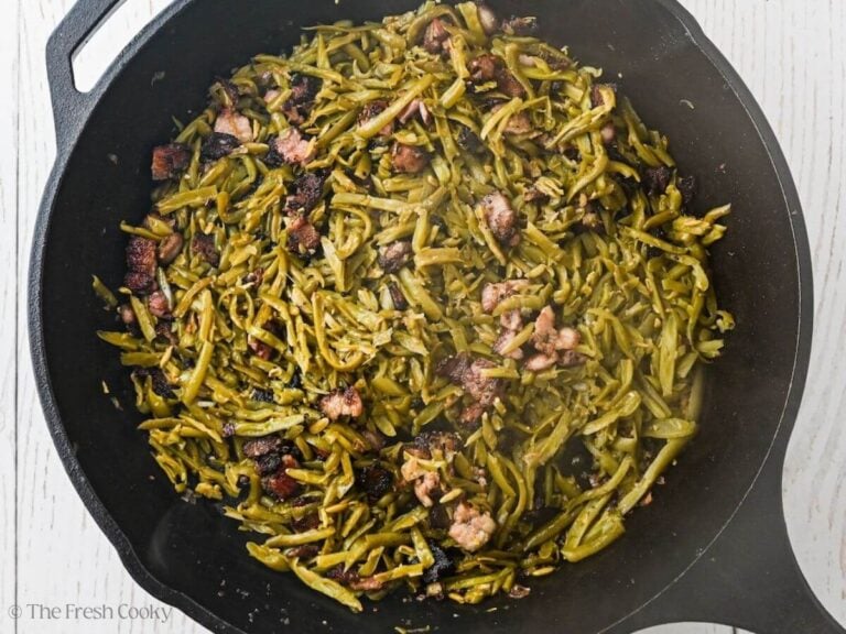 Green beans tossed with shallots, garlic and cooked crispy bacon in a cast iron skillet.