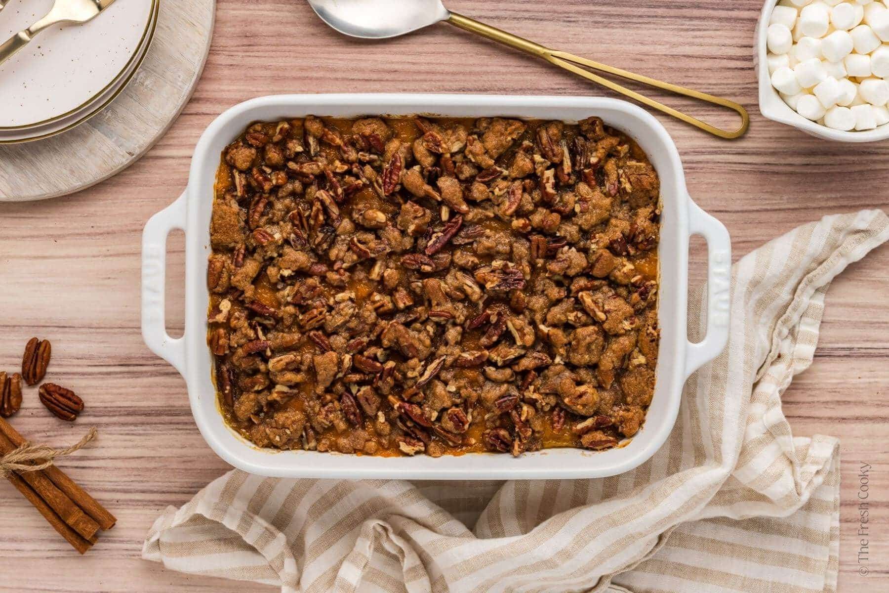 Sweet potato casserole with a pecan streusel topping in a white baking dish.
