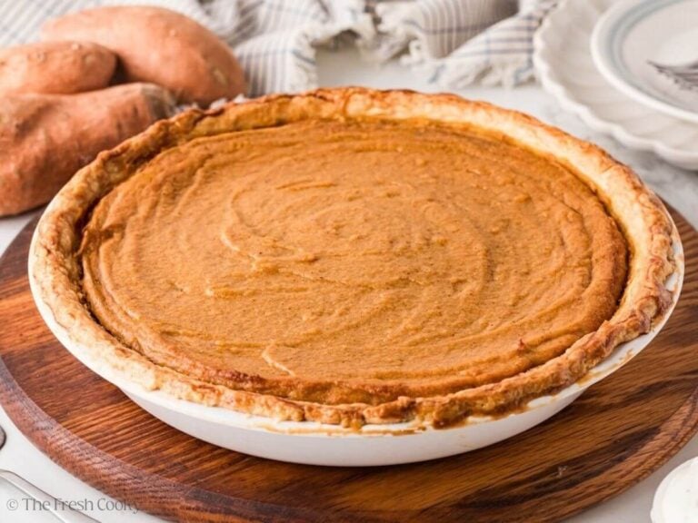 Side view of a sweet potato pie in a white pie dish on a wooden board.