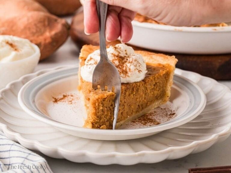 Fork taking a bite of sweet potato pie on a plate.
