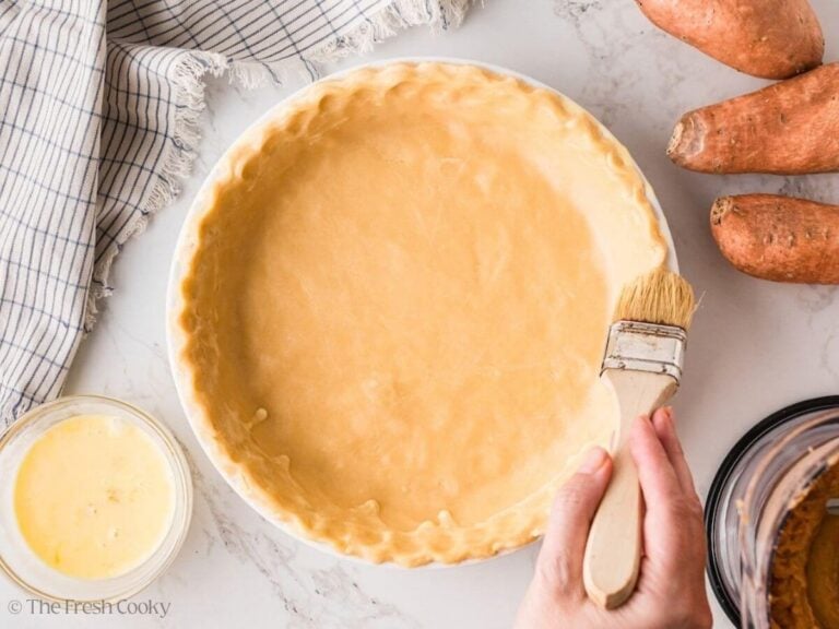 Brushing the edges of a pie crust with egg wash.