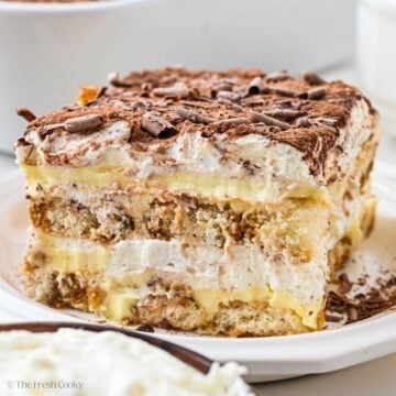 A cream slice of tiramisu on a white plate.