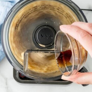 Adding vanilla extract to almond paste in a food processor.