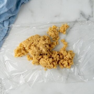 Almond paste placed in a piece of plastic wrap before wrapping it up.