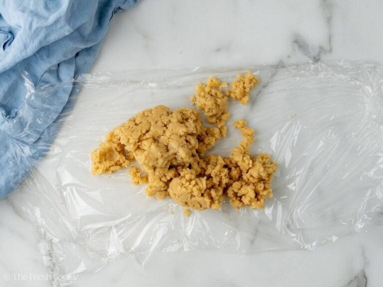 Almond paste placed in a piece of plastic wrap before wrapping it up.