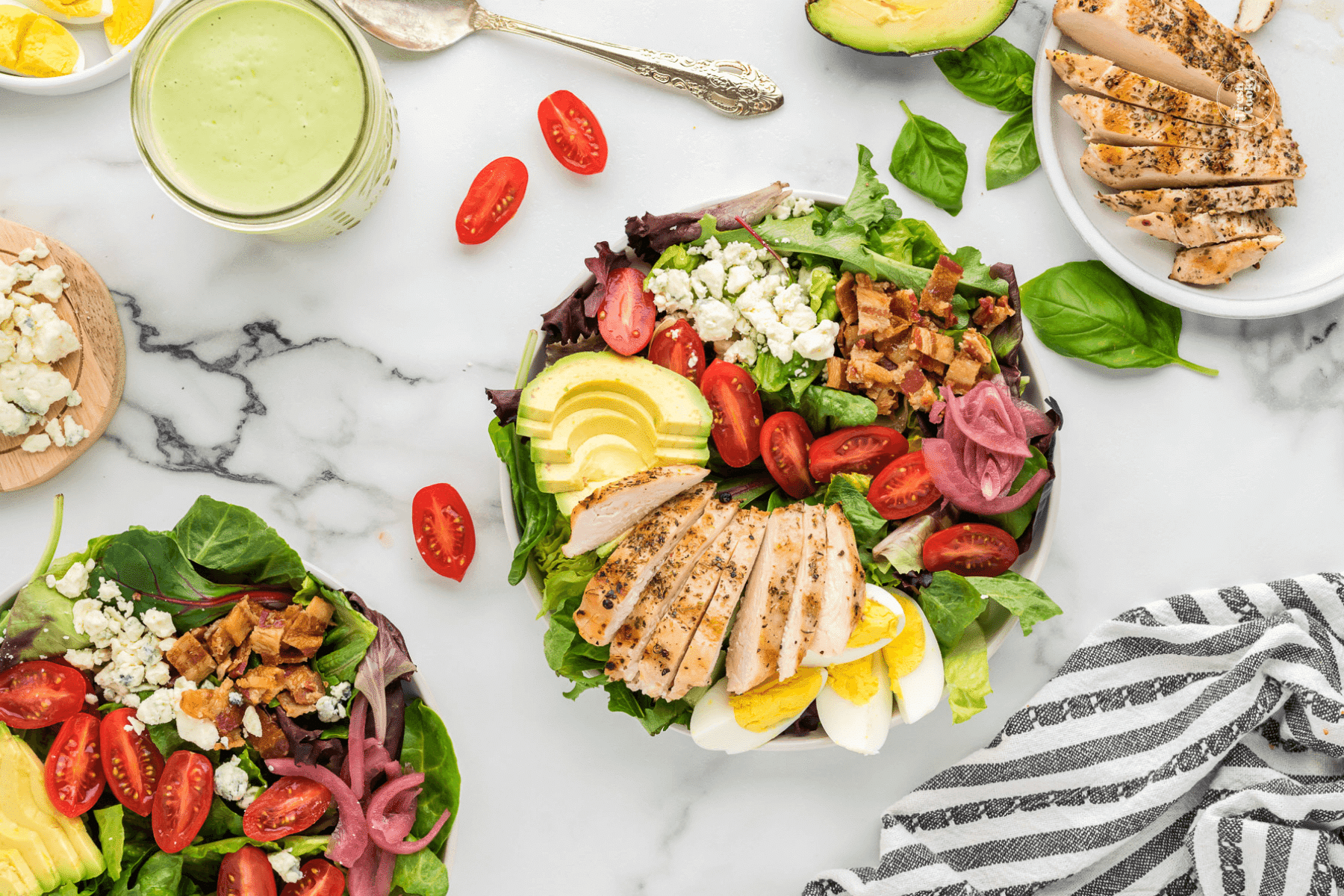 Adding chicken to plated green goddess salad.