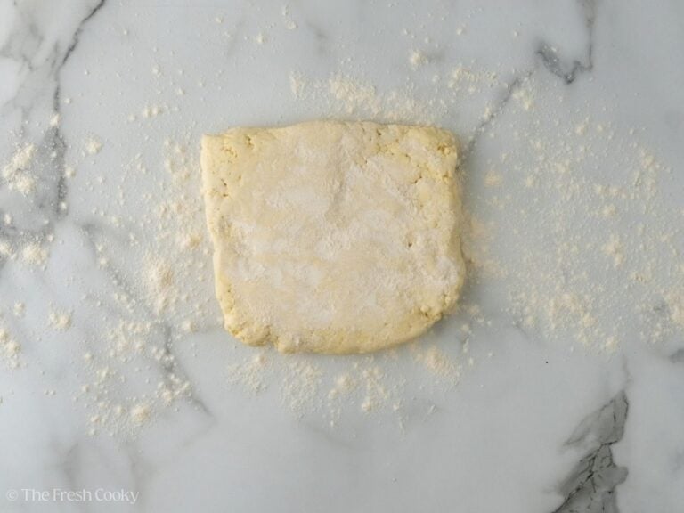 Chilled dough sprinkled with flour on marble.