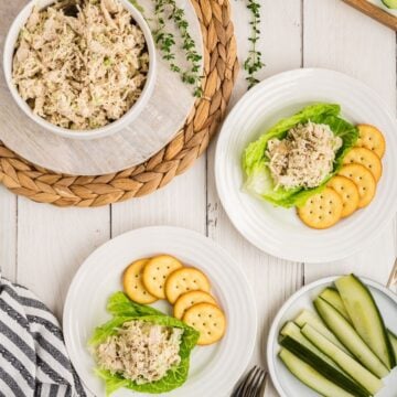 Classic Carol chicken salad in bowl and scooped onto lettuce on plates with crackers and dill pickle spears.
